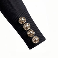 Black ribbed sweater with decorative buttons on a white background